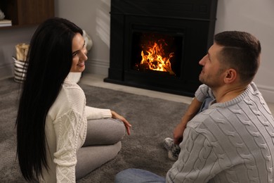 Lovely couple spending time together near fireplace at home