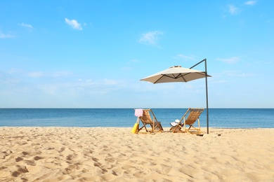 Empty wooden sunbeds and beach accessories on sandy shore