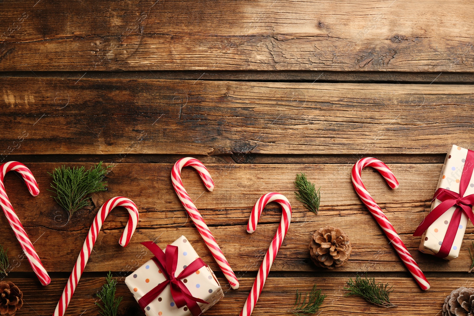 Photo of Flat lay composition with candy canes and Christmas decor on wooden background. Space for text