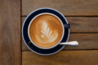 Cup of aromatic coffee on wooden table, top view