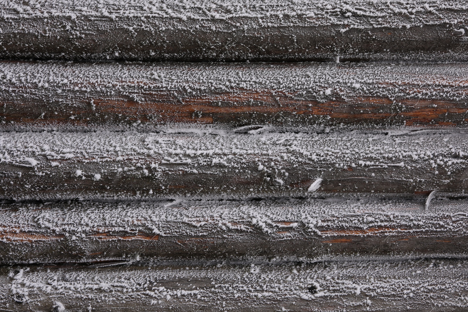 Photo of Wooden wall covered with hoarfrost on snowy day, closeup