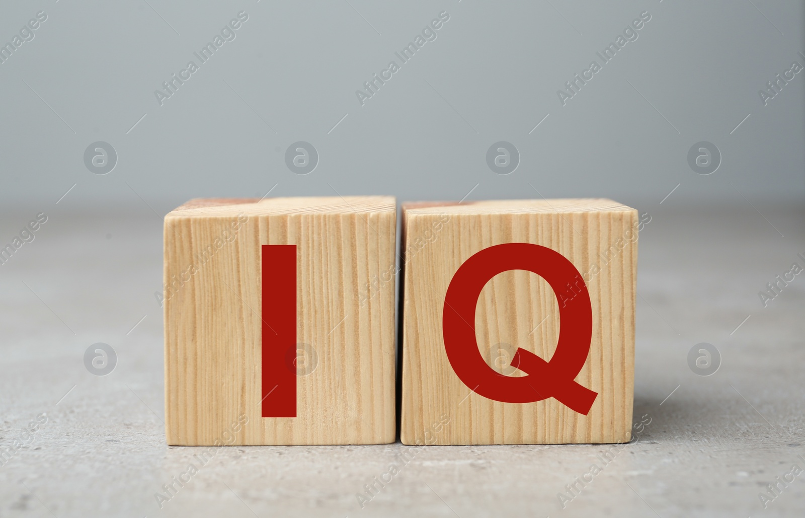 Photo of Wooden cubes with abbreviation IQ on light grey stone table