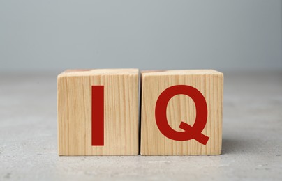 Wooden cubes with abbreviation IQ on light grey stone table