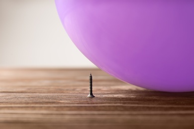 Color balloon and nail on table against white background, space for text