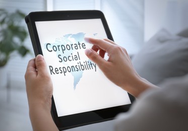 Corporate social responsibility concept. Woman with tablet indoors, closeup 