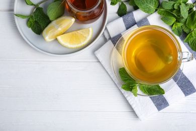 Photo of Fresh green tea with mint, honey and lemon on white wooden table, flat lay. Space for text