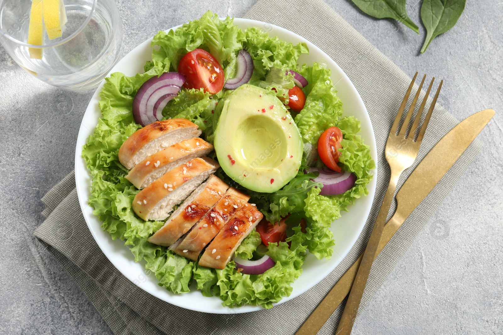 Photo of Delicious salad with chicken, avocado and vegetables served on light grey table, flat lay