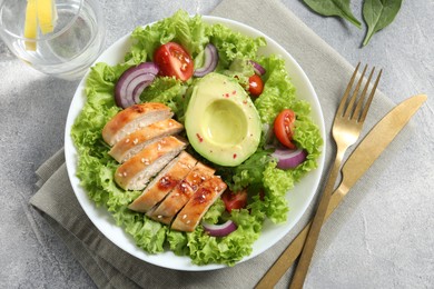 Delicious salad with chicken, avocado and vegetables served on light grey table, flat lay