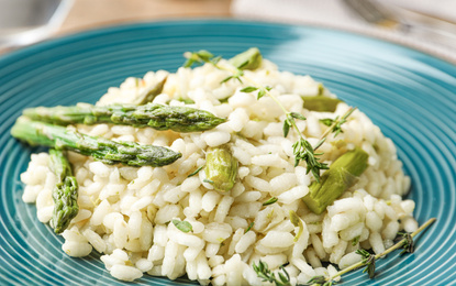 Photo of Delicious risotto with asparagus in plate, closeup