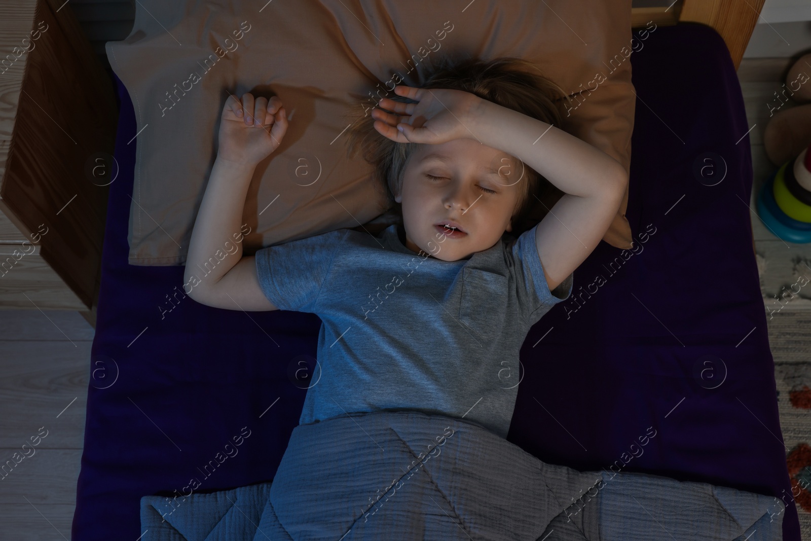 Photo of Little boy snoring while sleeping in bed at night, top view