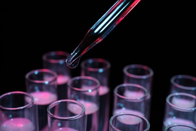 Photo of Dripping reagent into test tube on black background, closeup. Laboratory analysis