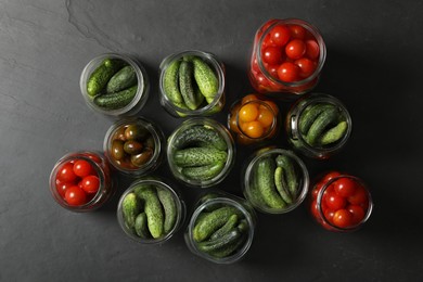 Photo of Pickling jars with fresh vegetables on black table, flat lay