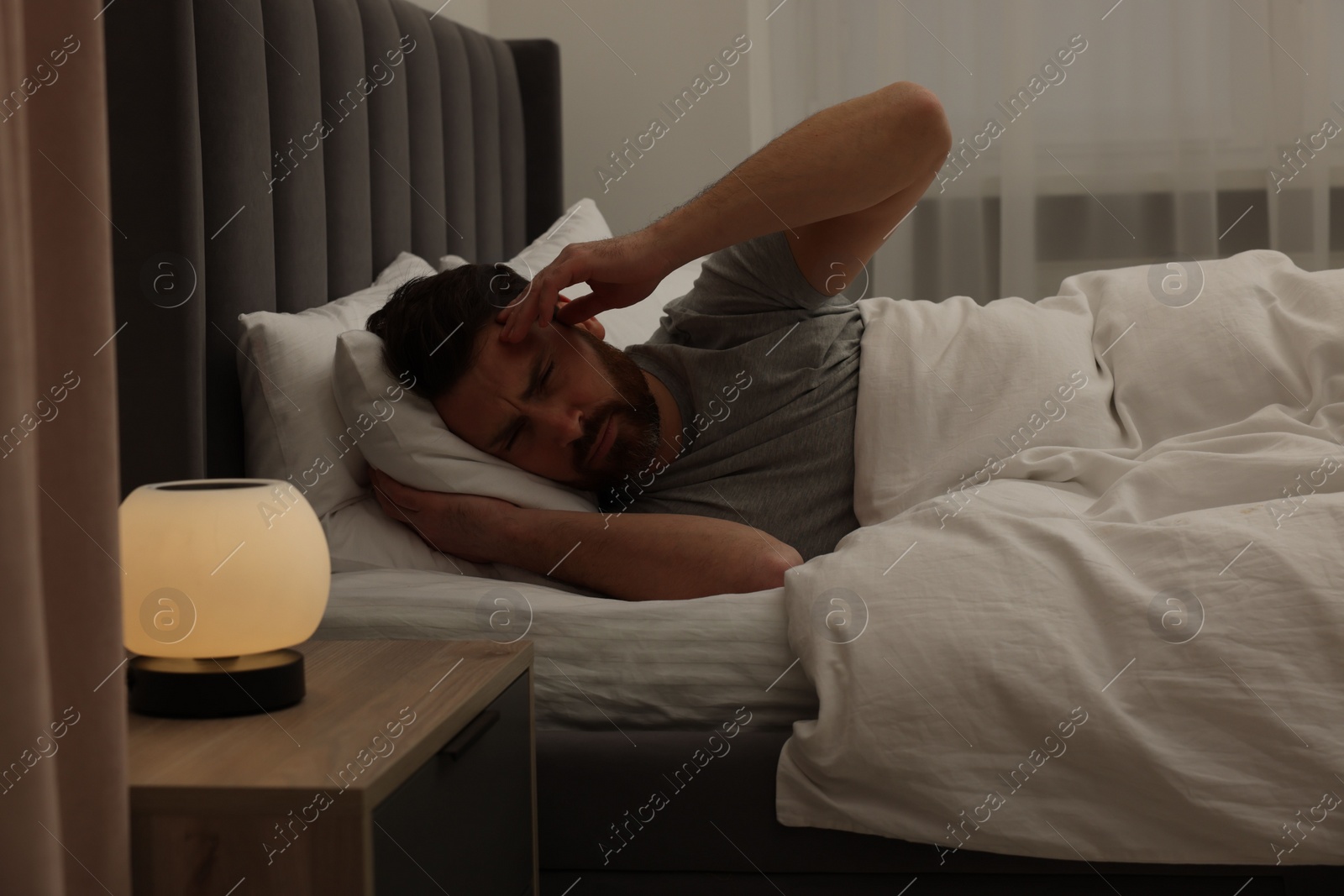 Photo of Man suffering from headache in bed at night