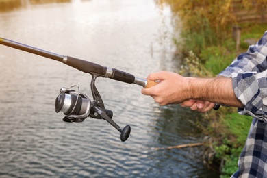 Man with rod fishing at riverside, focus on hands. Recreational activity