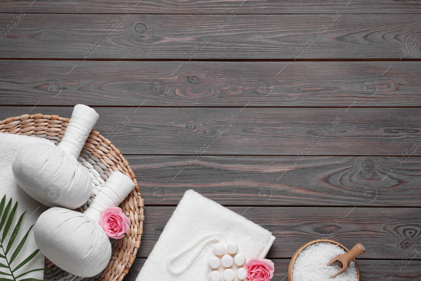 Photo of Flat lay composition of herbal bags and spa products on grey wooden table, space for text