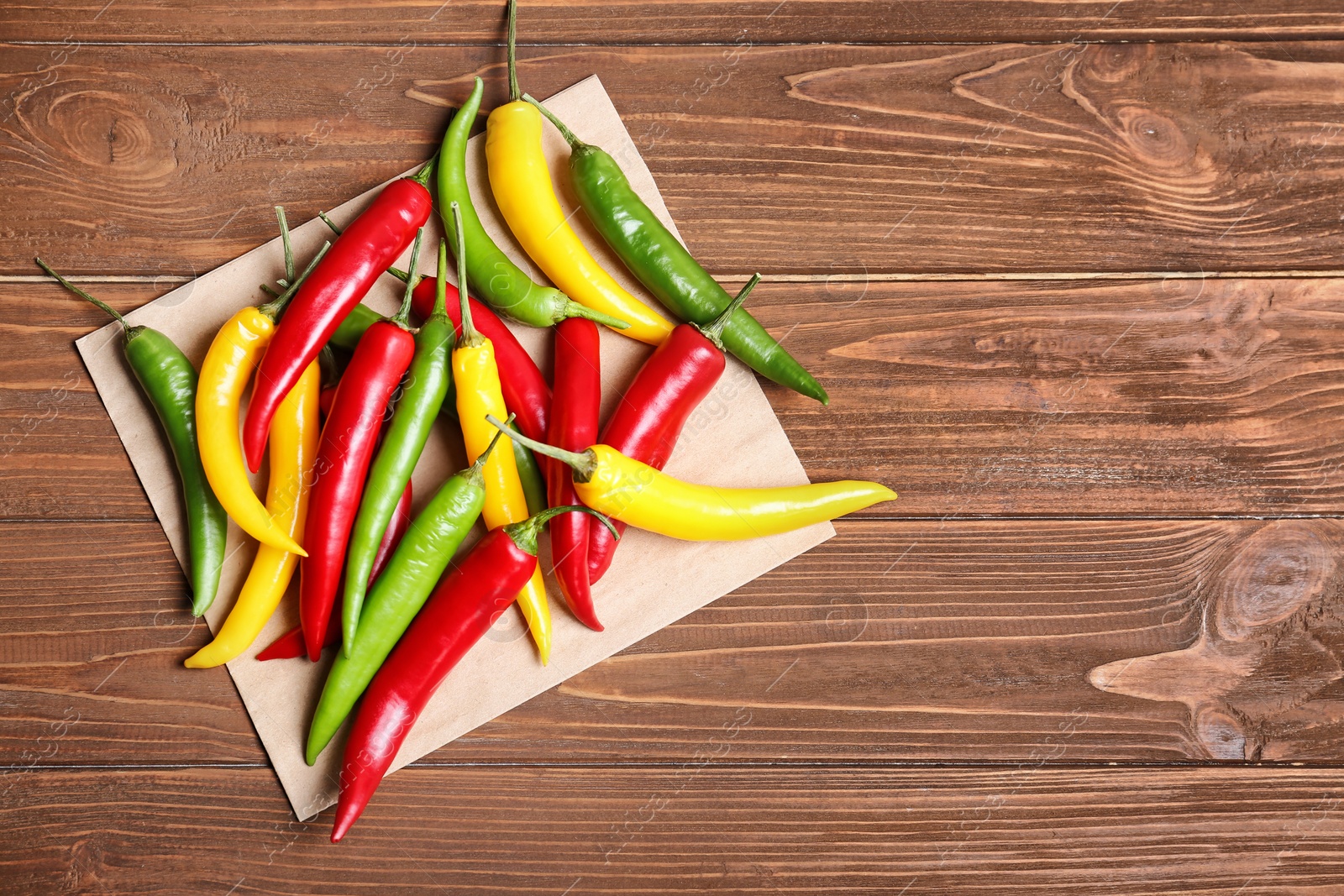 Photo of Ripe chili peppers on wooden background, top view