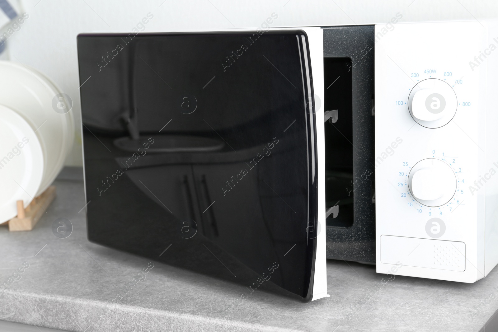 Photo of Open modern microwave oven on table in kitchen