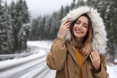 Young woman in warm clothes outdoors, space for text. Winter vacation