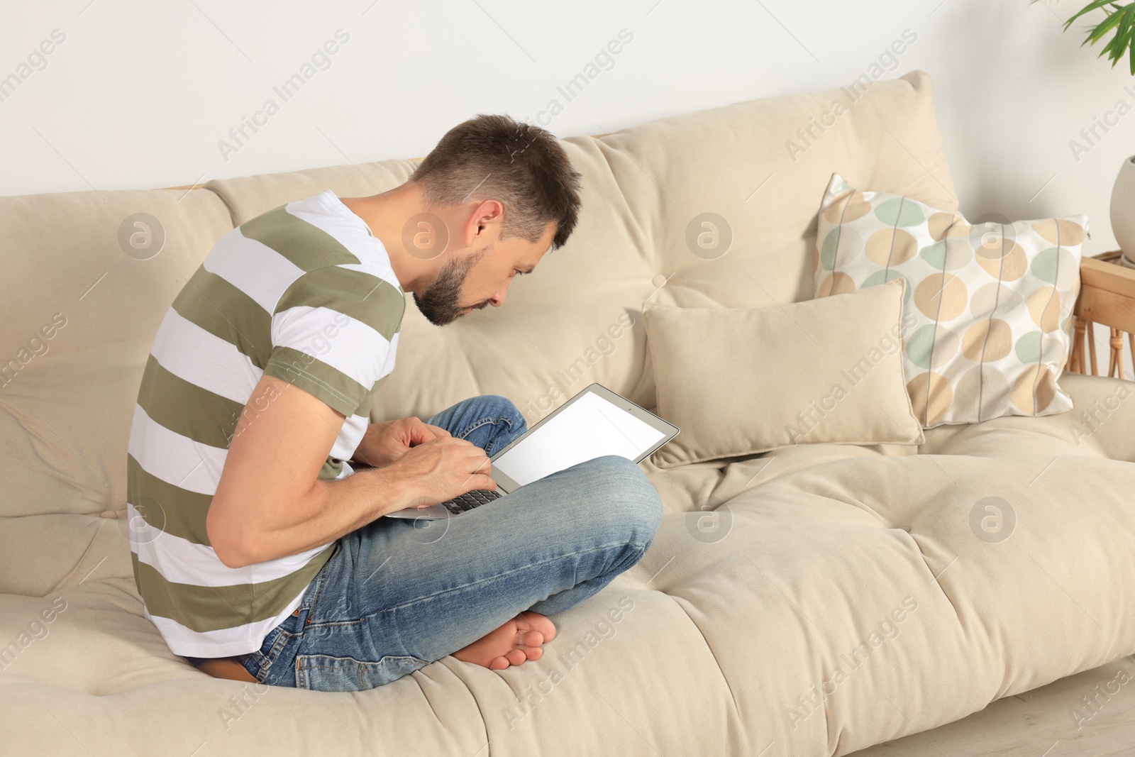 Photo of Man with poor posture using laptop on sofa at home