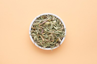 Photo of Bowl with aromatic dried lemongrass on beige background, top view