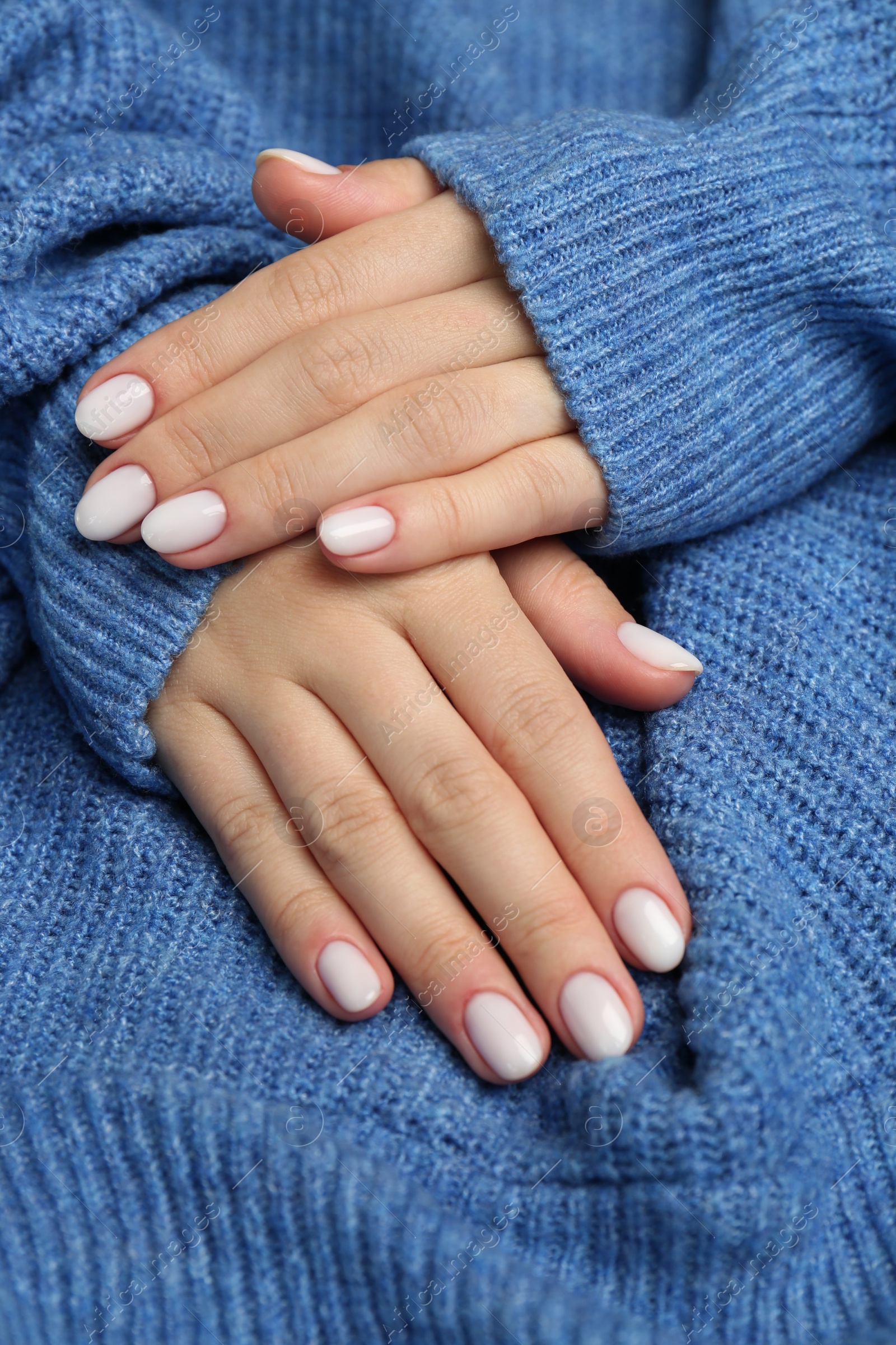 Photo of Woman showing her manicured hands with white nail polish, closeup