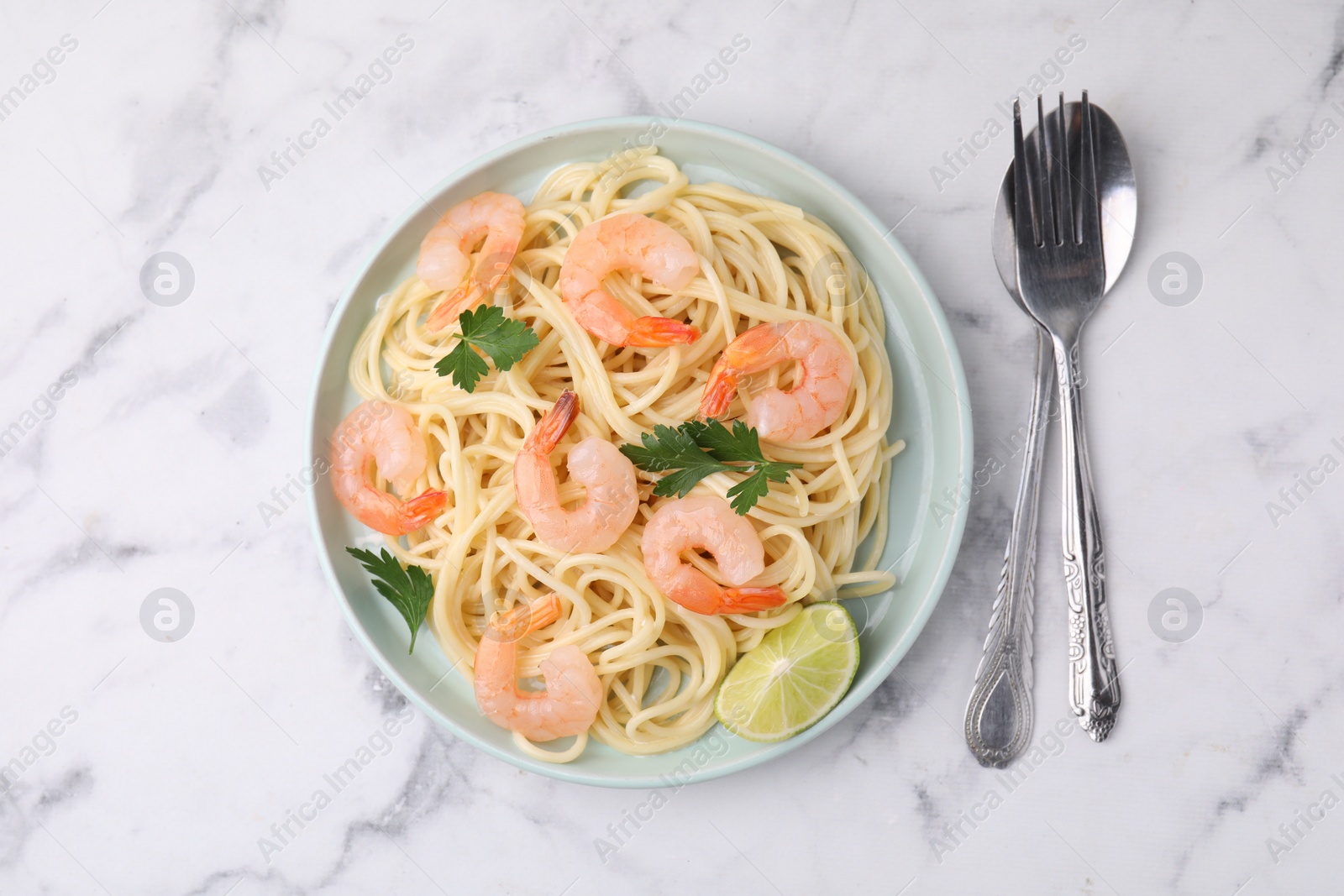 Photo of Tasty spaghetti with shrimps, lime and parsley served on white marble table, top view