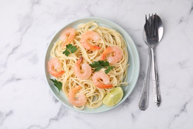 Photo of Tasty spaghetti with shrimps, lime and parsley served on white marble table, top view