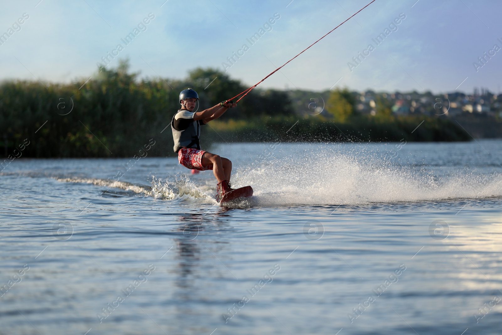 Photo of Teenage boy wakeboarding on river. Extreme water sport