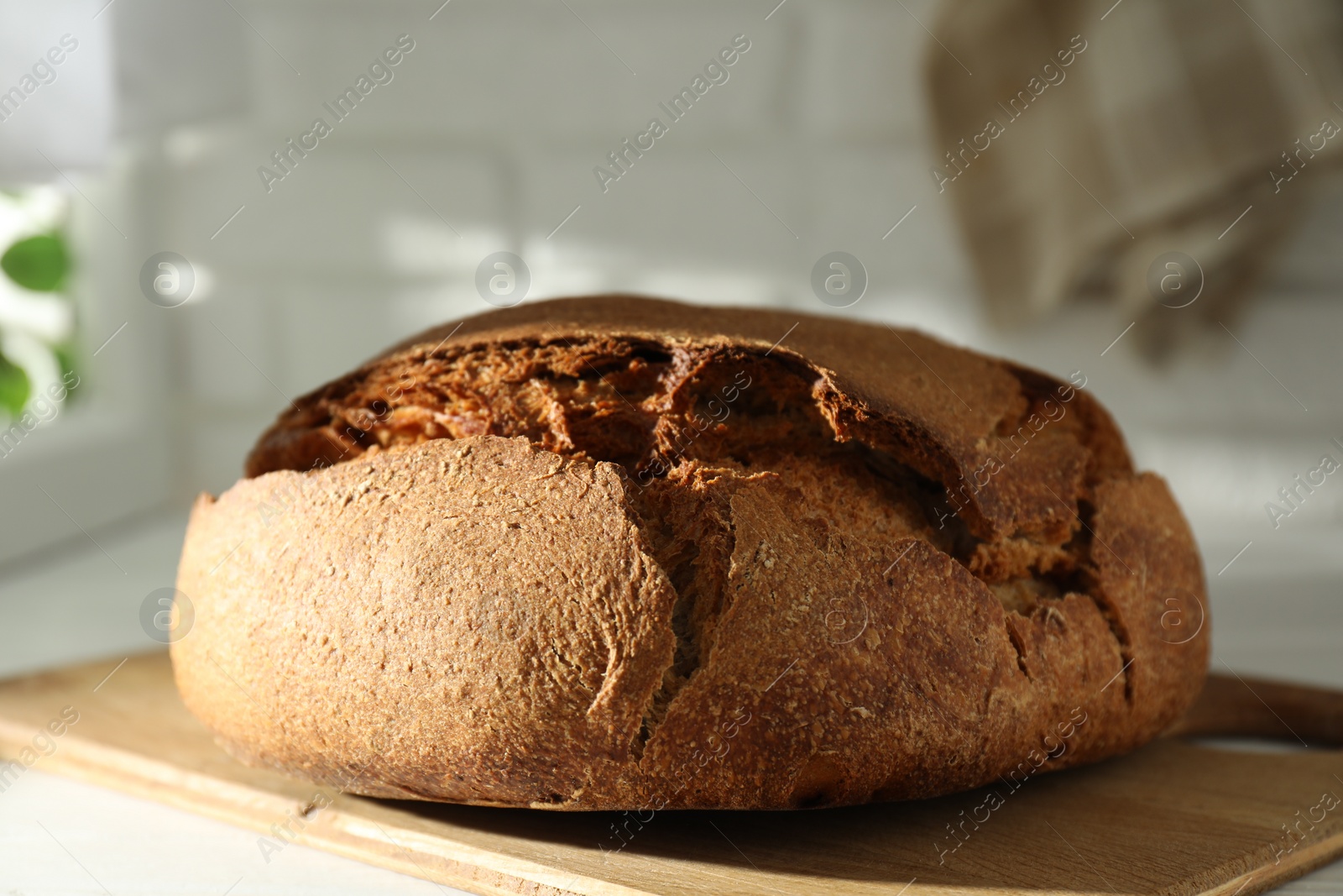 Photo of Freshly baked sourdough bread on white wooden table indoors