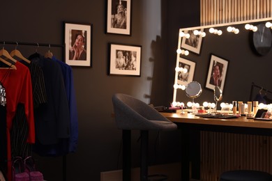 Photo of Chair, clothes rack and stylish mirror on dressing table in makeup room