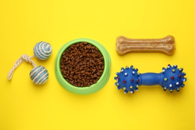 Photo of Different pet toys and food on yellow background, flat lay
