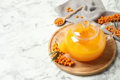 Photo of Delicious sea buckthorn tea and fresh berries on white marble table. Space for text