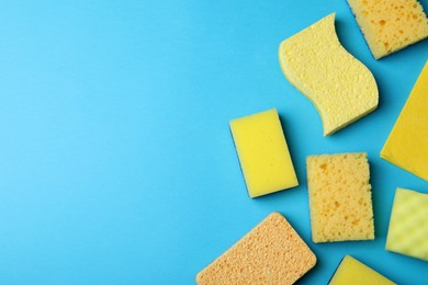 Photo of Many different sponges on light blue background, flat lay. Space for text