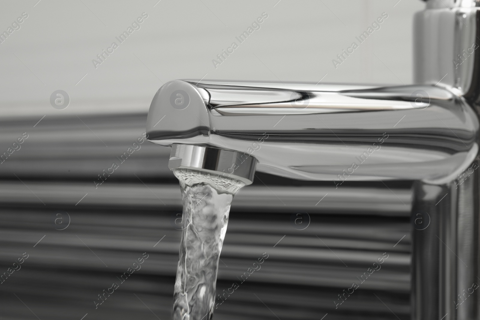 Photo of Water flowing from tap on blurred background, closeup