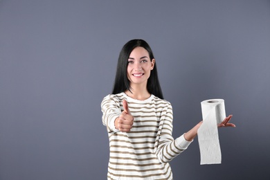Photo of Beautiful woman holding toilet paper roll on color background