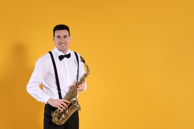 Photo of Young man in elegant outfit with saxophone on yellow background. Space for text