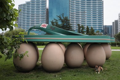 Batumi, Georgia - June 24, 2022: Dog near beautiful art installation Sea Slippers on Eggs