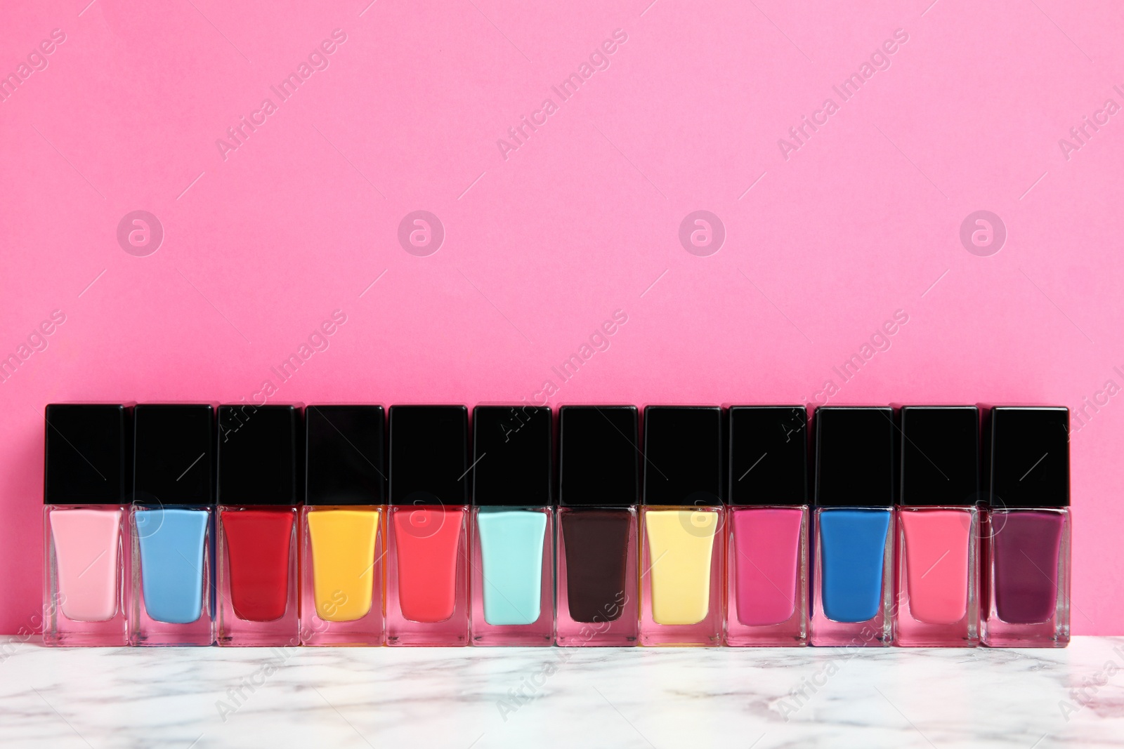 Photo of Bright nail polishes on table against color background. Space for text