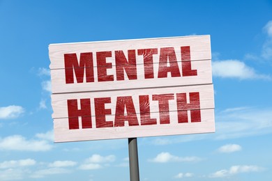 Image of Wooden sign with phrase Mental Health against blue sky on sunny day