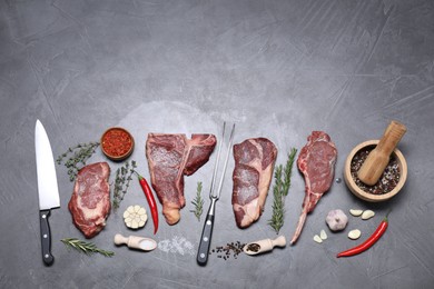 Photo of Fresh raw beef cuts, butcher tools and different spices on light grey textured table, flat lay. Space for text