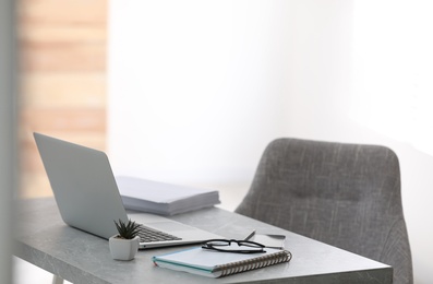 Modern workplace with laptop on grey table in office