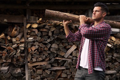 Man with log near wood pile outdoors