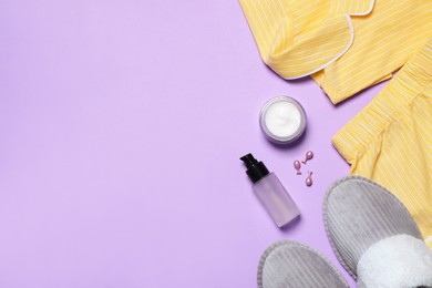 Flat lay composition with pajamas and skin care products on violet background, space for text