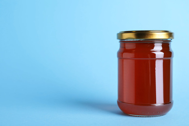 Jar of organic honey on light blue background. Space for text