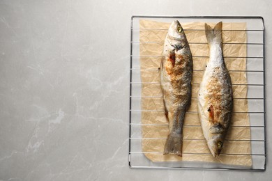 Photo of Baked fish on light marble table, top view. Space for text