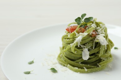 Photo of Tasty tagliatelle with spinach and cheese on plate, closeup. Exquisite presentation of pasta dish