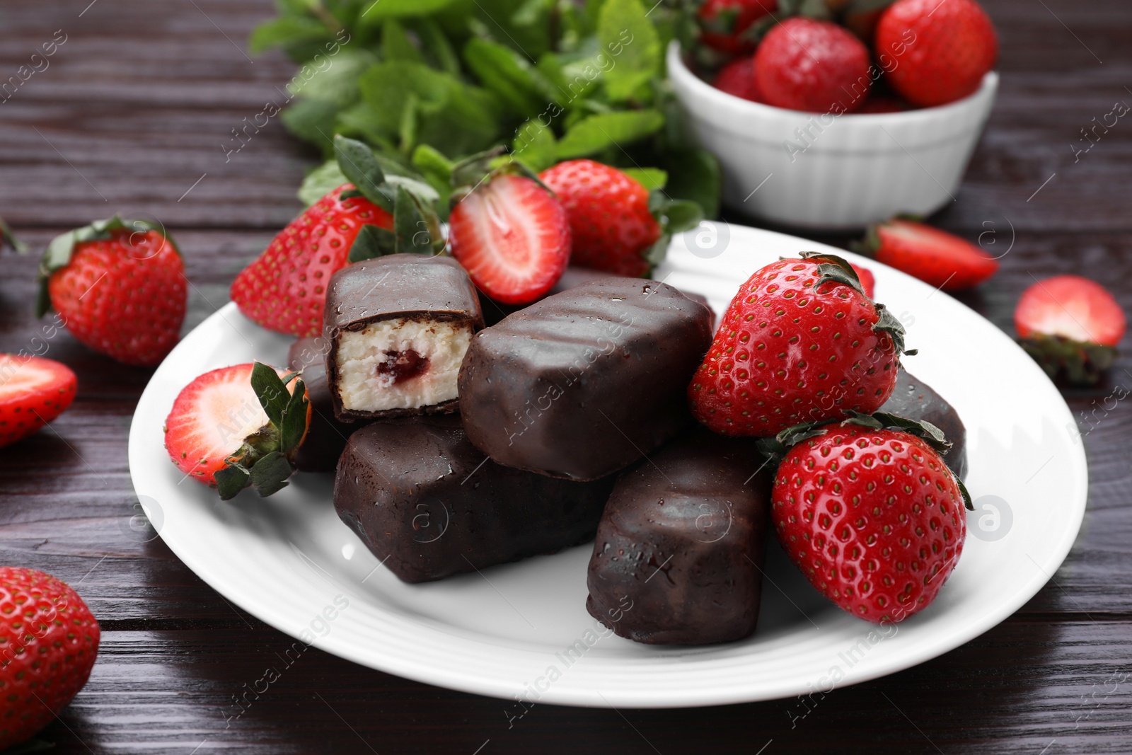 Photo of Delicious glazed curds, mint leaves and fresh strawberries on wooden table