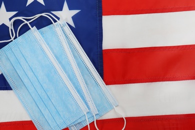 Photo of Protective masks on American flag, flat lay. Coronavirus pandemic in USA