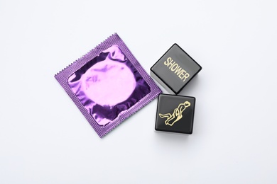 Photo of Sex dice and condom on white background, top view