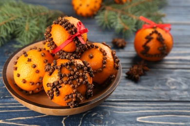 Pomander balls made of fresh tangerines and cloves on blue wooden table, space for text